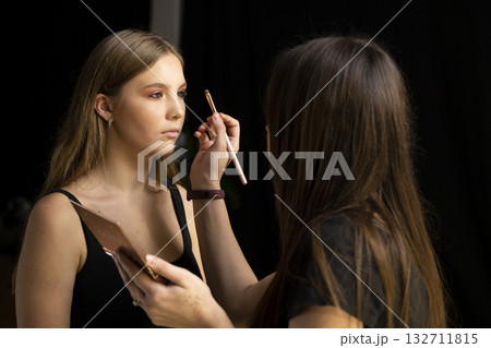 Makeup artist applying eye shadow with brush on young woman in beauty studio Makeup artist applying eye shadow with brush on young woman in beauty studio 132711815