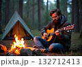 A person relaxing while sitting next to a campfire on a beach, playing a guitar 132712413
