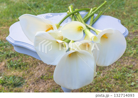 Bunch of white calla lilies on a white table outdoors Bunch of white calla lilies on a white table outdoors 132714093