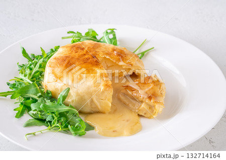 Melted Camembert en Croute with rosemary garnish and vibrant cranberry sauce accompaniment Melted Camembert en Croute with rosemary garnish and vibrant cranberry sauce accompaniment 132714164