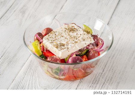Fresh traditional Greek salad topped with thick feta slice served in glass bowl 132714191