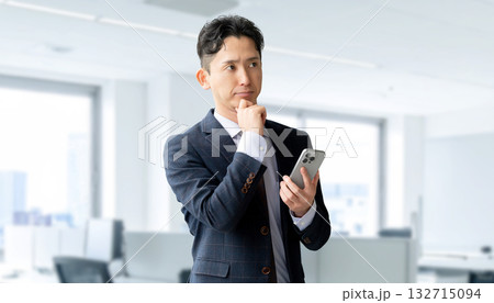 スマートフォンを持って考える男性ビジネスマン 132715094