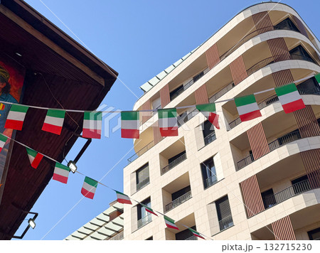 Italian flags hanging across the street between buildings. Celebration, national identity and Mediterranean atmosphere. Italian flags hanging across the street between buildings. Celebration, national identity and Mediterranean atmosphere. 132715230