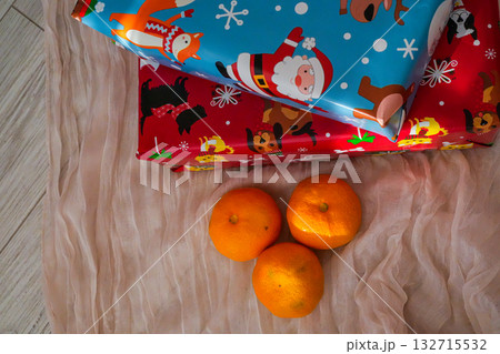 Two wrapped Christmas gift boxes accompanied by fresh tangerines. Festive holiday composition with seasonal colors, perfect for Christmas, New Year, and winter themes. Two wrapped Christmas gift boxes accompanied by fresh tangerines. Festive holiday composition with seasonal colors, perfect for Christmas, New Year, and winter themes. 132715532