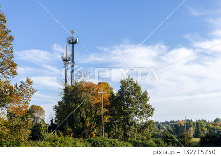 Metal communication towers among autumn trees create contrast in peaceful rural landscape 132715750