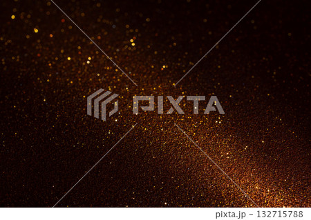 Illuminated brown glitter texture glowing from lower right with golden fragments across deep shadow Illuminated brown glitter texture glowing from lower right with golden fragments across deep shadow 132715788