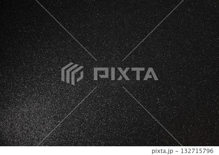 Sharp focused black glitter surface with fine grain soft glowing light and scattered bright sparkles 132715796