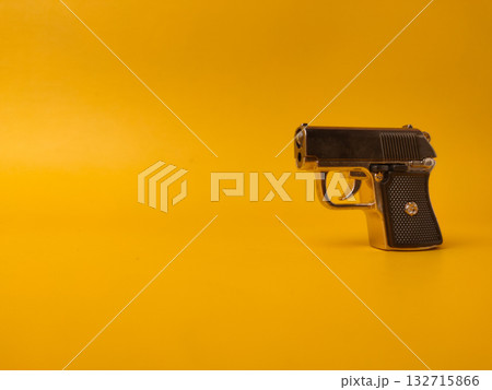 A small handgun is on a yellow background with copy and text space. A small handgun is on a yellow background with copy and text space. 132715866
