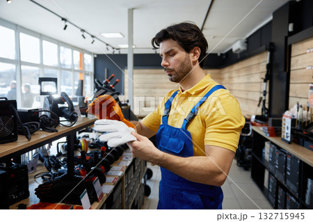 Male young worker holds two pairs of gloves Male young worker holds two pairs of gloves 132715945