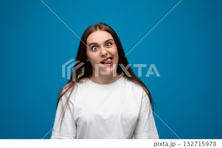 Funny young woman making silly face with tongue out on blue background 132715978