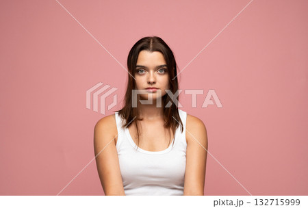 Calm young woman with straight brown hair and green eyes posing on pink background Calm young woman with straight brown hair and green eyes posing on pink background 132715999