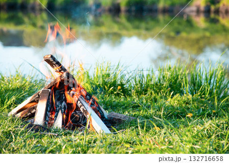Burning fire on the shore of the reservoir 132716658