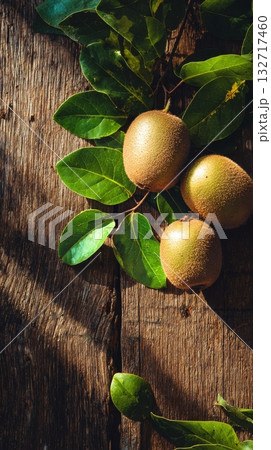Fresh Sapotes Surrounded by Green Leaves on Rustic Wooden Table in Natural Light 132717460