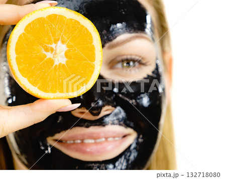 Girl black carbo mask on face holds orange fruit 132718080