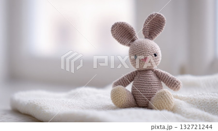 Crocheted Bunny Toy On Soft Blanket In Bright Room. Handmade Craft For Children'S Comfort And Play 132721244