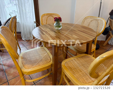 Wooden cafe table with chairs and flower vase. Cozy atmosphere, natural materials, and warm interior design 132721520