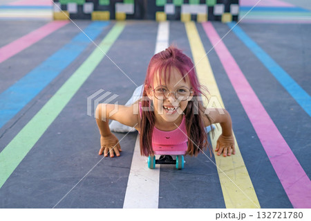 Funny laughing preschool girl skateboarding on the playground of the skate park Funny laughing preschool girl skateboarding on the playground of the skate park 132721780