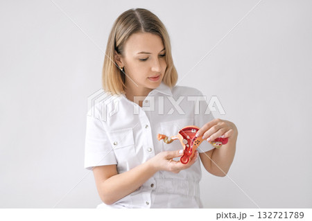 A female doctor talks about neoplasms, tumors and cancer in gynecology, showing an anatomical model of the uterus 132721789