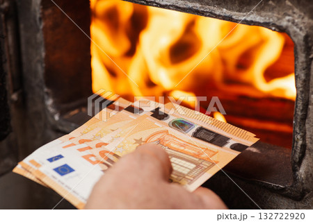 Man throwing euro money in the boiler with bright flames in it. Concept of high prices for heating the house, shortage of fuel and need to save money Man throwing euro money in the boiler with bright flames in it. Concept of high prices for heating the house, shortage of fuel and need to save money 132722920