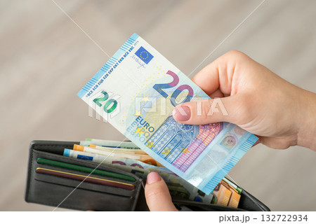 Hands of a girl holding 20 euro bill and wallet full of money, close up. Finances, business in Europe, making purchases concept Hands of a girl holding 20 euro bill and wallet full of money, close up. Finances, business in Europe, making purchases concept 132722934