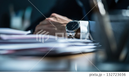 Businessman Timepiece On Wrist Over Desk With Papers In Office Setting Businessman Timepiece On Wrist Over Desk With Papers In Office Setting 132723036