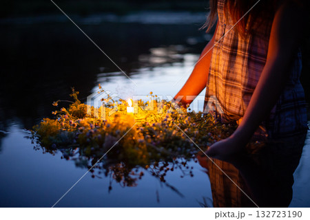 Wreath made with wild flowers with a candle in the middle. Girl following old slavic traditions on day of Ivana Kupala 132723190