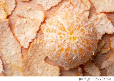 Close-up shot of peeled out tangerine with many peels around. Tasty juicy tangerine on a table Close-up shot of peeled out tangerine with many peels around. Tasty juicy tangerine on a table 132723208