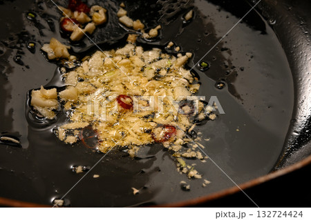 ニンニクと唐辛子をオリーブオイルで炒める様子 132724424