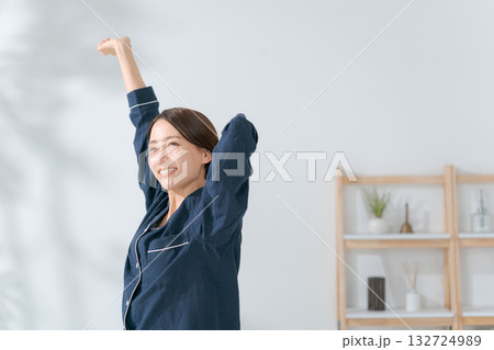 伸びをするパジャマの女性 132724989