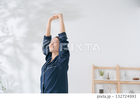伸びをするパジャマの女性 132724991