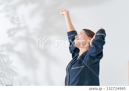 伸びをするパジャマの女性 132724995