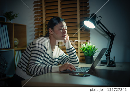 sleepy woman working with laptop at a night 132727241