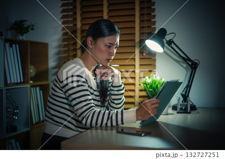 woman thinking while using tablet at night woman thinking while using tablet at night 132727251