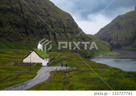 A scenic view of the village of Saksun in the Faroe Islands, featuring traditional houses with grass roofs nestled in a lush, green valley. High quality photo 132727781