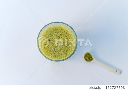 A vibrant green matcha drink alongside a bowl of fine matcha powder, presented on a clean white background for a fresh and minimalistic look. A vibrant green matcha drink alongside a bowl of fine matcha powder, presented on a clean white background for a fresh and minimalistic look. 132727898