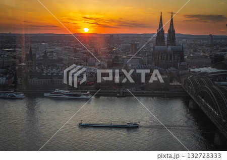 A breathtaking view of the Cologne skyline during sunset featuring the iconic Cologne Cathedral and the city's famous bridge. The warm hues of the evening sky create a stunning scene in Germany. A breathtaking view of the Cologne skyline during sunset featuring the iconic Cologne Cathedral and the city's famous bridge. The warm hues of the evening sky create a stunning scene in Germany. 132728333