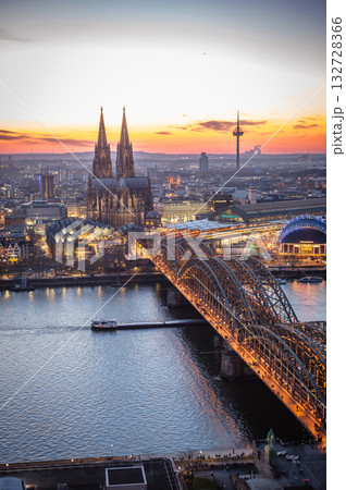 A breathtaking view of the Cologne skyline right after sunset featuring the iconic Cologne Cathedral and the city's famous bridge. The warm hues of the evening sky create a stunning scene in Germany. A breathtaking view of the Cologne skyline right after sunset featuring the iconic Cologne Cathedral and the city's famous bridge. The warm hues of the evening sky create a stunning scene in Germany. 132728366