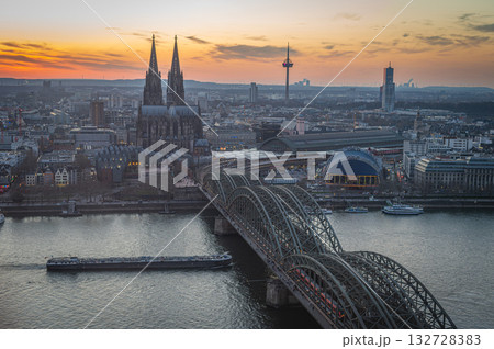 A breathtaking view of the Cologne skyline during sunset featuring the iconic Cologne Cathedral and the city's famous bridge. The warm hues of the evening sky create a stunning scene in Germany. A breathtaking view of the Cologne skyline during sunset featuring the iconic Cologne Cathedral and the city's famous bridge. The warm hues of the evening sky create a stunning scene in Germany. 132728383