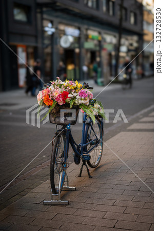 Bycicle parked in the street in Cologne with flowers in busket. Cologne street in the background. Bycicle parked in the street in Cologne with flowers in busket. Cologne street in the background. 132728530