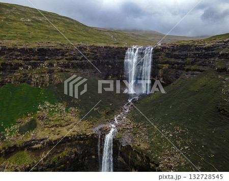 Magnificent Fossa waterfall, the highest in the Faroe Islands, cascading down rugged cliffs into the North Atlantic. Magnificent Fossa waterfall, the highest in the Faroe Islands, cascading down rugged cliffs into the North Atlantic. 132728545