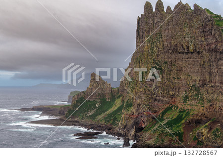 Close-up shot of famous Drangarnir cliff with Tindholmur islands in the background taken during early morning hike in spring at Faroese coastline Faroe Island, Denmark, Europe. High quality photo 132728567