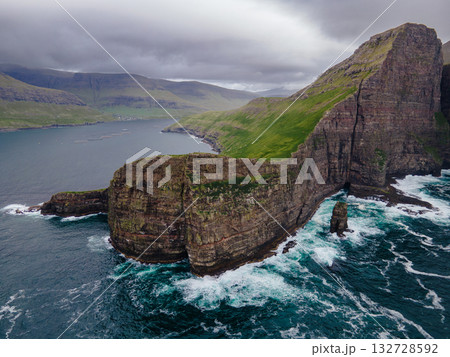 Close-up shot of famous Drangarnir cliff with Tindholmur islands in the background taken during early morning hike in spring at Faroese coastline Faroe Island, Denmark, Europe. High quality photo Close-up shot of famous Drangarnir cliff with Tindholmur islands in the background taken during early morning hike in spring at Faroese coastline Faroe Island, Denmark, Europe. High quality photo 132728592