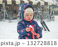 Outdoor winter portrait of little cute toddler girl in blue coat and white fashion hat. Healthy happy baby child playing in the park on cold day with snow and snowfall. Stylish clothes for kids 132728818