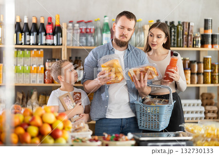 Couple of man and woman with boy choosing food in grocery 132730133