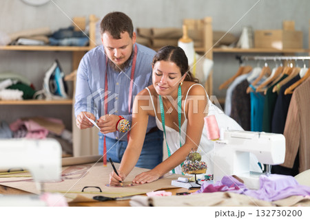 Female tailor sketching pattern with colleague in sewing studio Female tailor sketching pattern with colleague in sewing studio 132730200
