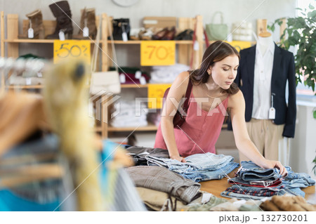 Young woman picking up jeans at a sale 132730201