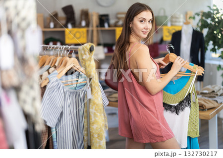 Young woman customer making choice and elect something summer clothing in store 132730217