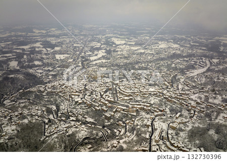 Aerial winter landscape of dense historic center of Thiers town in Puy-de-Dome department, Auvergne-Rhone-Alpes region in France. Rooftops of old buildings and narrow streets at snowfall 132730396