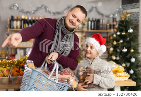 Dad and son are choosing products for New Year celebration in supermarket Dad and son are choosing products for New Year celebration in supermarket 132730420