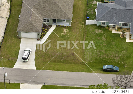 Aerial view of typical contemporary american private house with roof top covered with asphalt shingles and green lawn on yard Aerial view of typical contemporary american private house with roof top covered with asphalt shingles and green lawn on yard 132730421